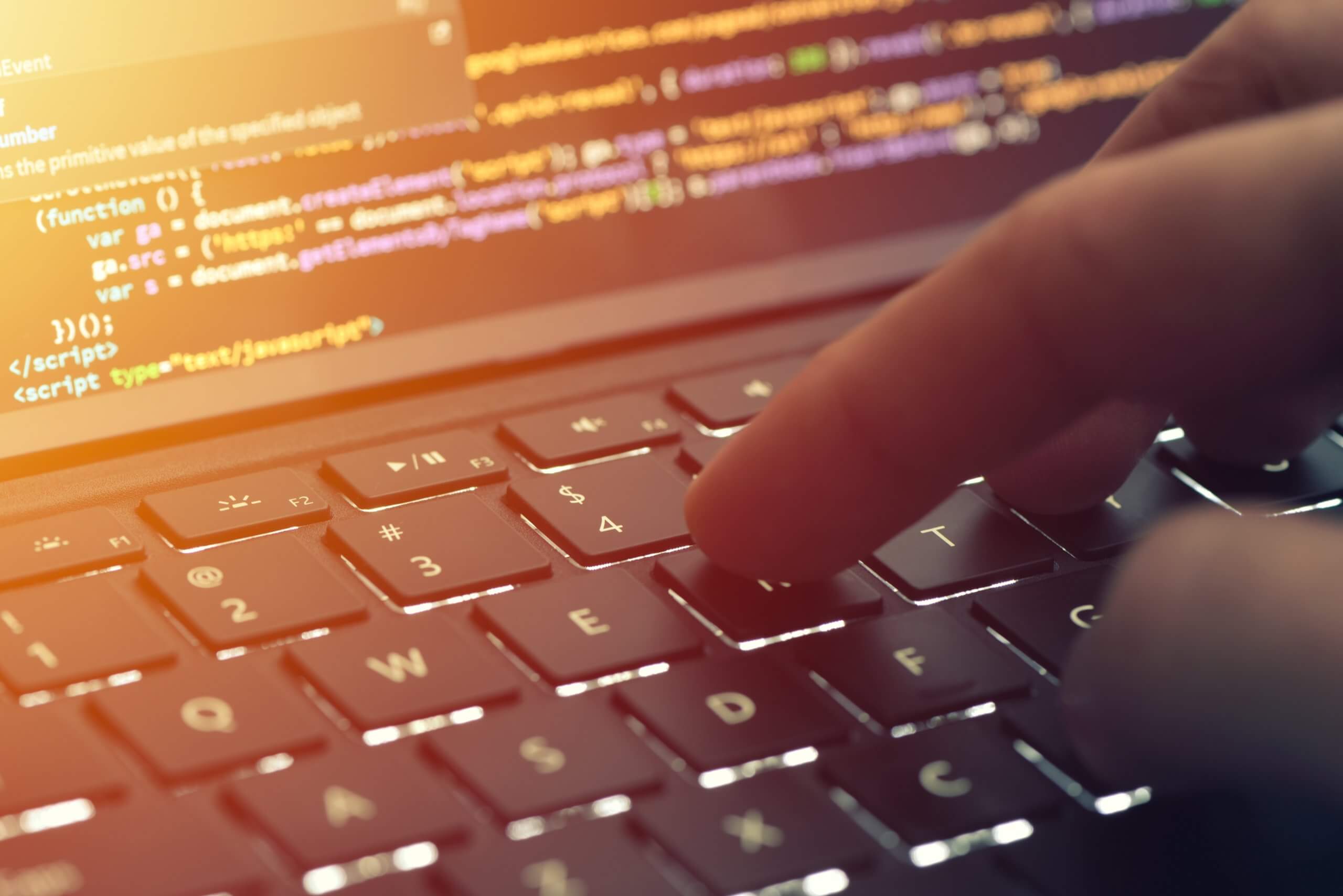 a close-up showing keyboard, a hand and a screen with some code